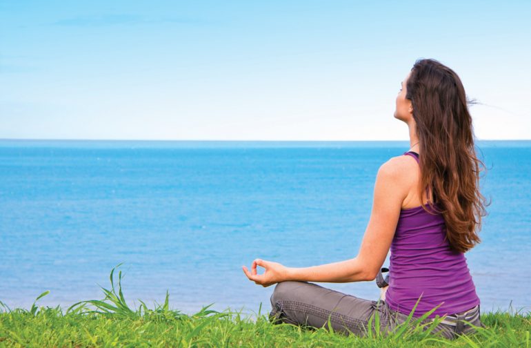 woman meditating by the ocean